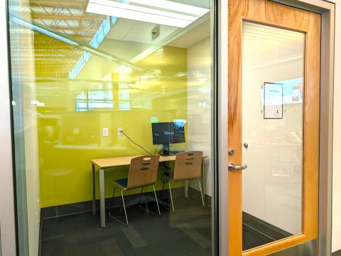 Image of Study Room 4. A table and two chairs are visible through a glass wall. 